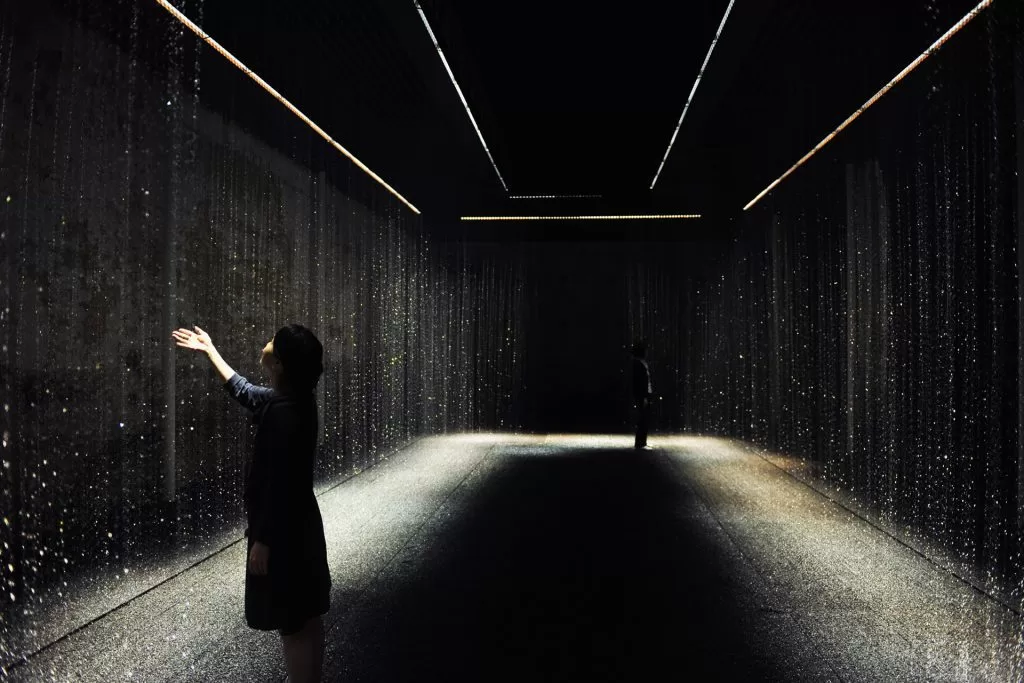 Woman interacts with an artistic fountain installation, part of fontane artistiche.